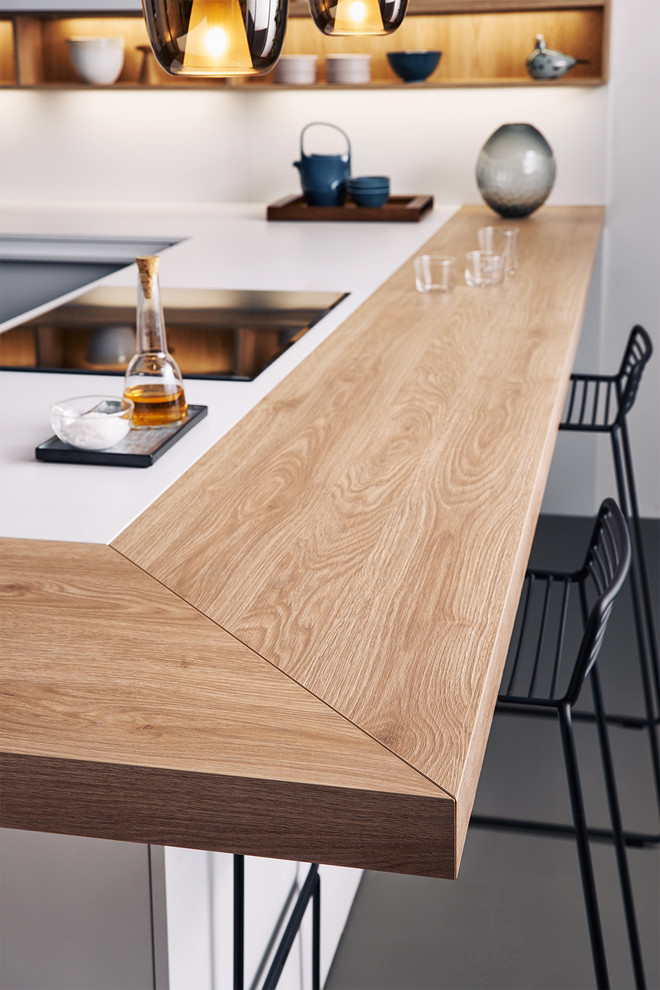 Idee per una cucina a L minimalista di medie dimensioni con ante lisce, ante bianche, top in legno e penisola