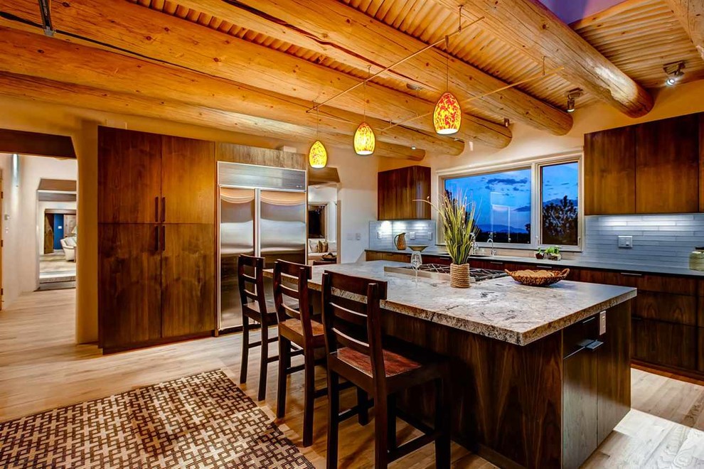 Inspiration for a large southwestern l-shaped medium tone wood floor eat-in kitchen remodel in Albuquerque with flat-panel cabinets, dark wood cabinets, granite countertops, gray backsplash, subway tile backsplash, stainless steel appliances, an island and an undermount sink