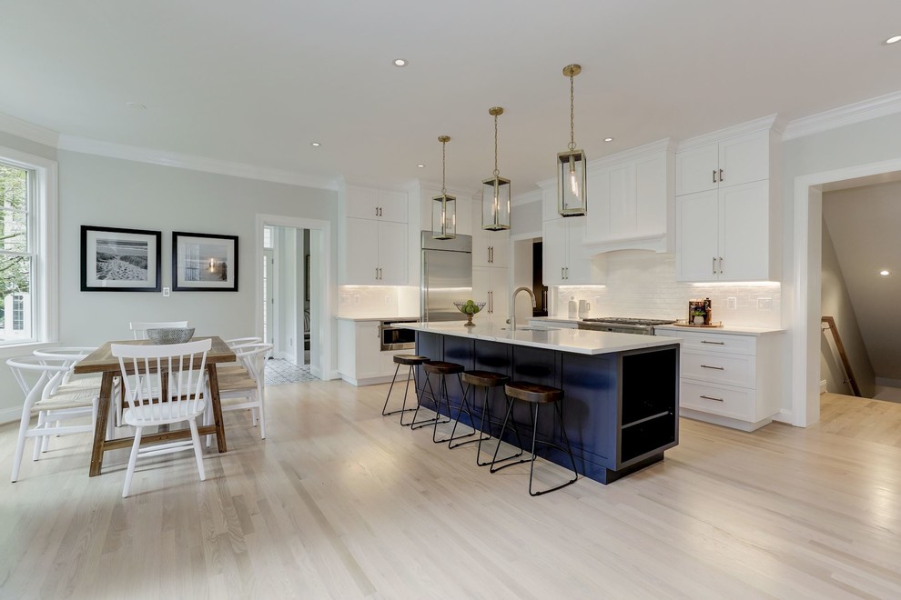 Large transitional light wood floor eat-in kitchen photo in DC Metro with a farmhouse sink, white cabinets, quartzite countertops, white backsplash, stainless steel appliances, an island and white countertops