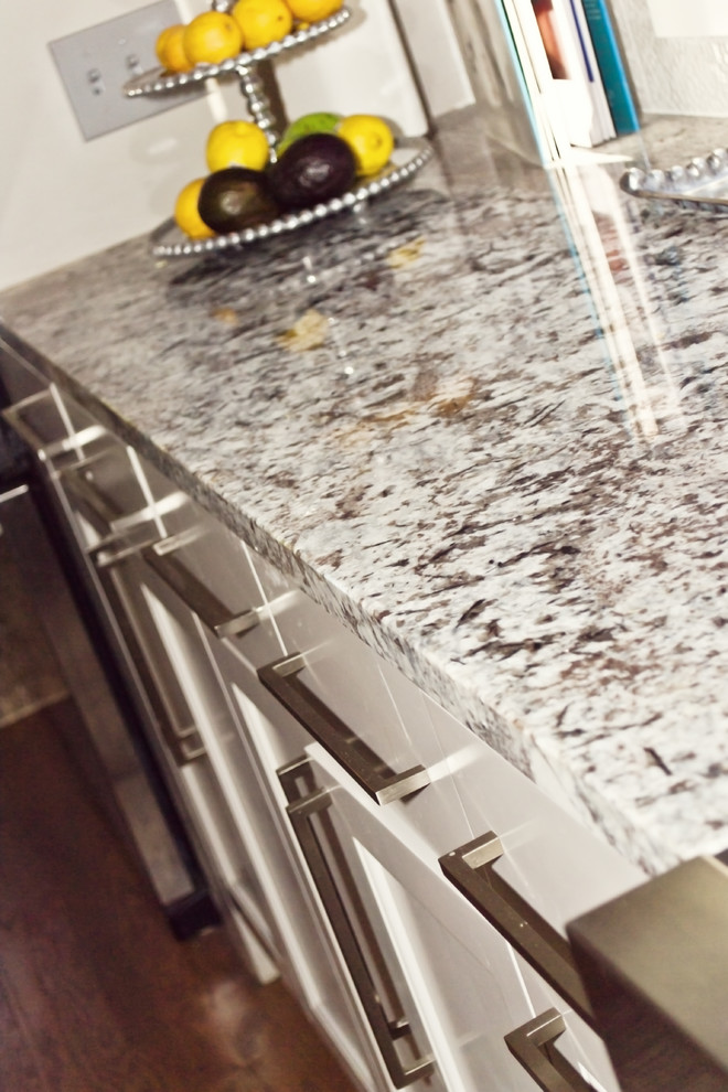 Klassische Küche mit Granit-Arbeitsplatte, Küchenrückwand in Weiß, Rückwand aus Porzellanfliesen, Unterbauwaschbecken, weißen Schränken, Küchengeräten aus Edelstahl, hellem Holzboden und beigem Boden in Oklahoma City