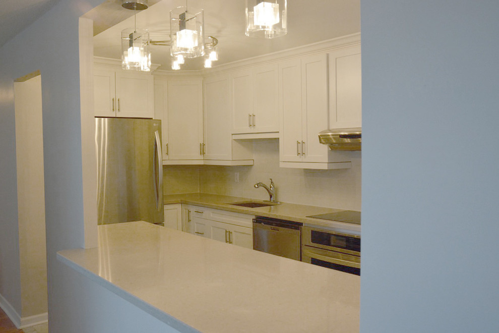 Esempio di una cucina ad U moderna chiusa e di medie dimensioni con lavello sottopiano, ante a filo, ante bianche, paraspruzzi bianco e elettrodomestici in acciaio inossidabile