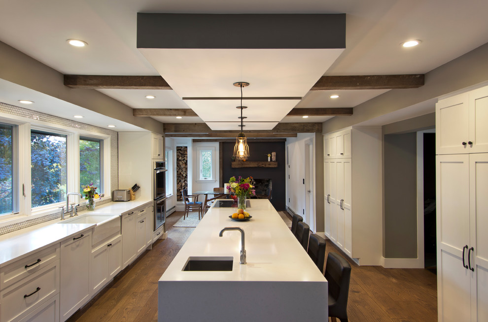 Inspiration for a large contemporary single-wall kitchen/diner in New York with a belfast sink, shaker cabinets, white cabinets, stainless steel appliances, medium hardwood flooring and an island.