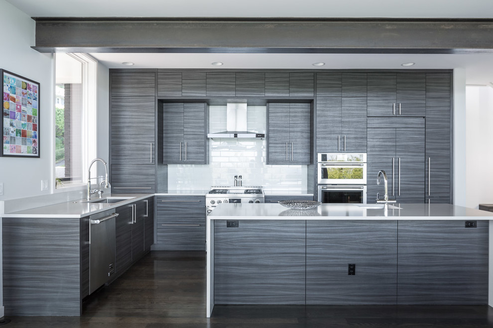 Inspiration for a modern galley dark wood floor and black floor kitchen remodel in Seattle with an undermount sink, flat-panel cabinets, gray cabinets, white backsplash, subway tile backsplash, stainless steel appliances and an island