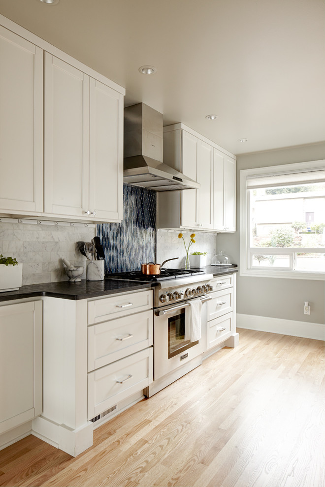 Photo of a medium sized traditional galley kitchen/diner in Seattle with shaker cabinets, white cabinets, onyx worktops, blue splashback, stone tiled splashback, stainless steel appliances, no island, a submerged sink and light hardwood flooring.