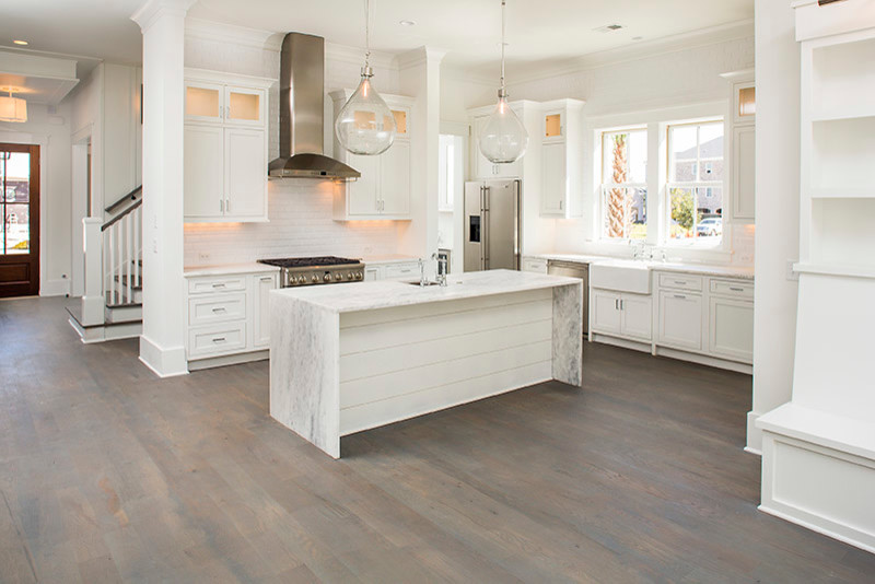 Eat-in kitchen - mid-sized coastal l-shaped medium tone wood floor eat-in kitchen idea in Charleston with a farmhouse sink, shaker cabinets, white cabinets, quartzite countertops, white backsplash, subway tile backsplash, stainless steel appliances and an island