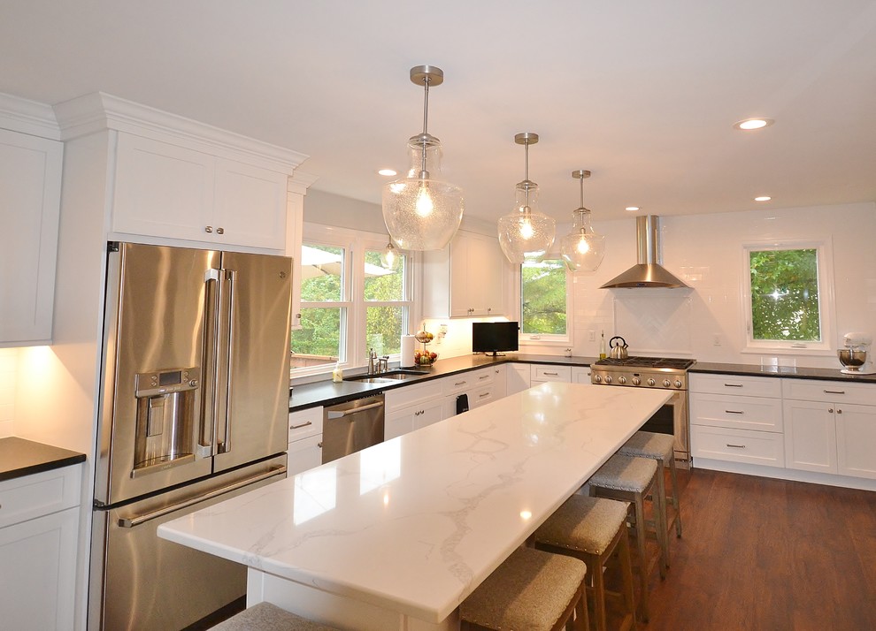 Huge transitional u-shaped vinyl floor and brown floor eat-in kitchen photo in Philadelphia with an undermount sink, recessed-panel cabinets, white cabinets, quartz countertops, white backsplash, subway tile backsplash, stainless steel appliances, an island and white countertops