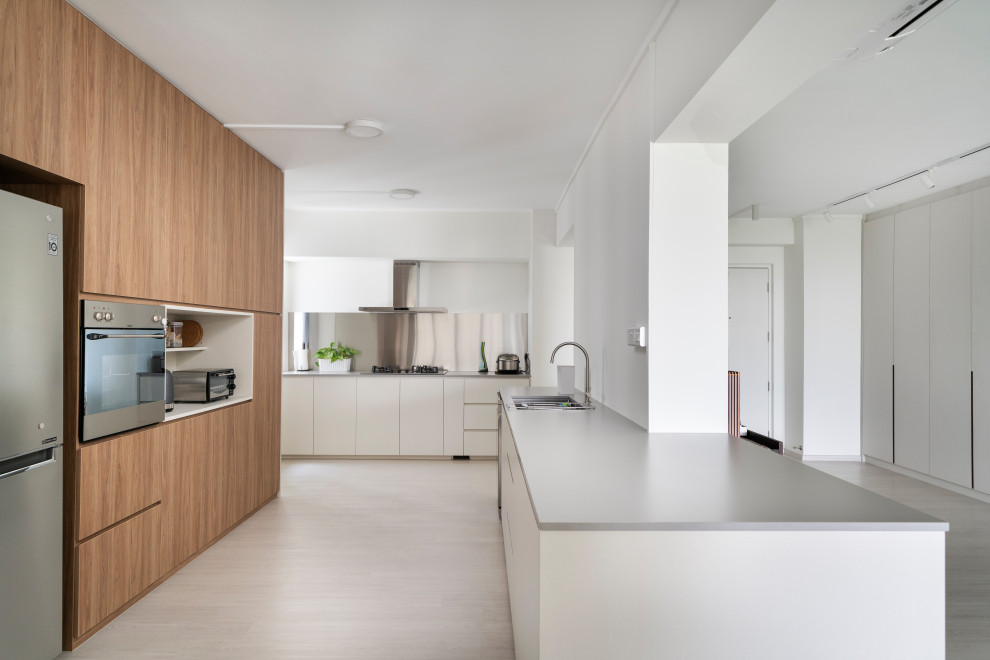 Contemporary l-shaped kitchen in Singapore with a submerged sink, flat-panel cabinets, white cabinets, metallic splashback, stainless steel appliances, a breakfast bar, grey floors and grey worktops.