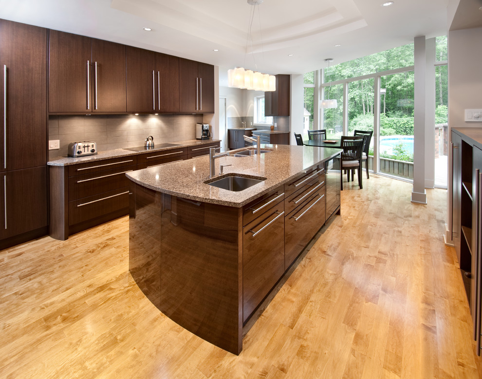 Exempel på ett stort modernt kök och matrum, med en undermonterad diskho, släta luckor, skåp i mörkt trä, beige stänkskydd, granitbänkskiva, rostfria vitvaror, ljust trägolv, en köksö och beiget golv