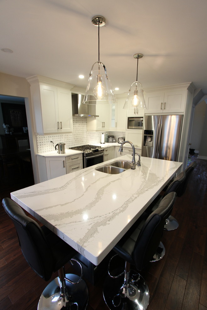 Medium sized contemporary l-shaped kitchen pantry in Toronto with a submerged sink, recessed-panel cabinets, white cabinets, engineered stone countertops, grey splashback, mosaic tiled splashback, stainless steel appliances, dark hardwood flooring, an island and red floors.