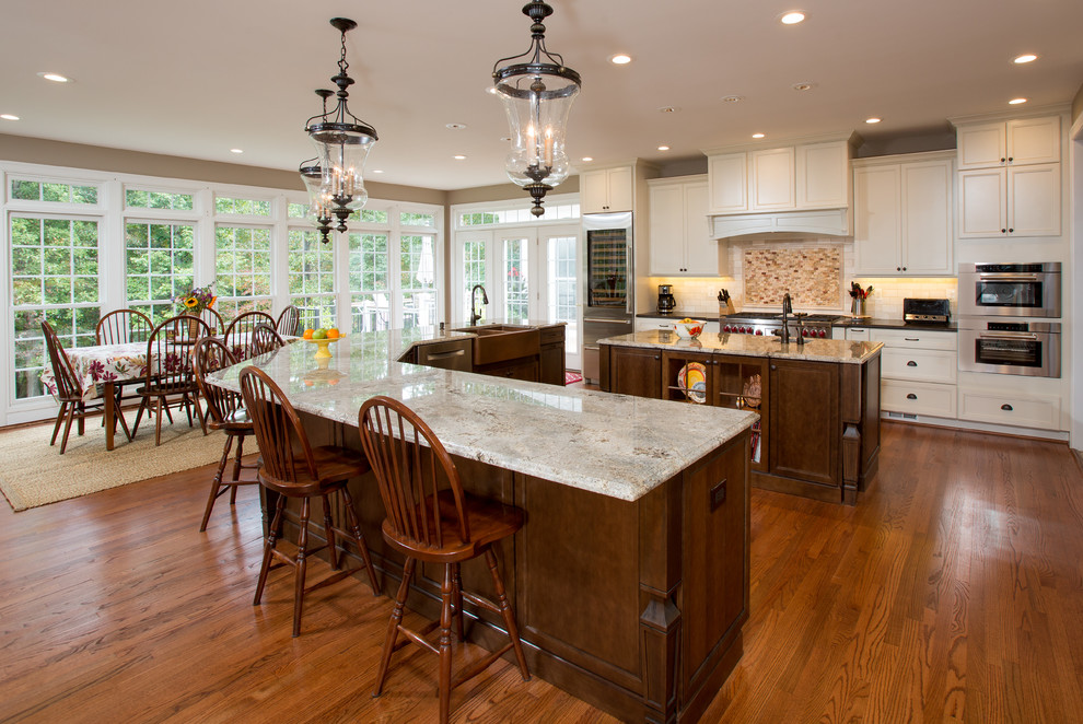 Große Klassische Küche mit weißen Schränken, Granit-Arbeitsplatte, Küchenrückwand in Beige, Küchengeräten aus Edelstahl, hellem Holzboden und zwei Kücheninseln in Washington, D.C.