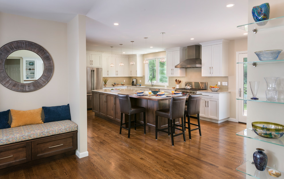 This is an example of a large traditional l-shaped open plan kitchen in Boston with an island, white cabinets, engineered stone countertops, grey worktops, shaker cabinets, glass tiled splashback, a submerged sink, beige splashback, stainless steel appliances, medium hardwood flooring and brown floors.