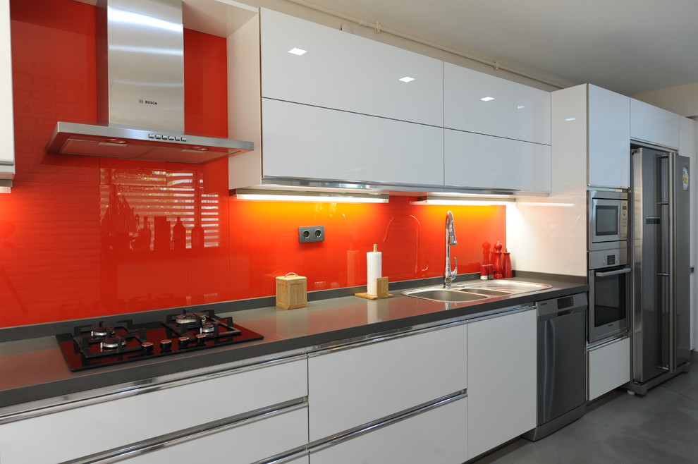Inspiration för ett funkis kök, med bänkskiva i kvarts, orange stänkskydd, glaspanel som stänkskydd och betonggolv