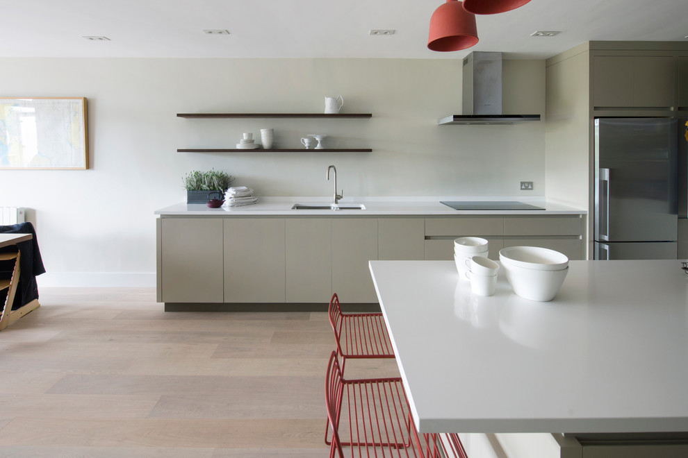 Contemporary open plan kitchen in Sussex with an integrated sink, flat-panel cabinets, grey cabinets, quartz worktops, stainless steel appliances and an island.