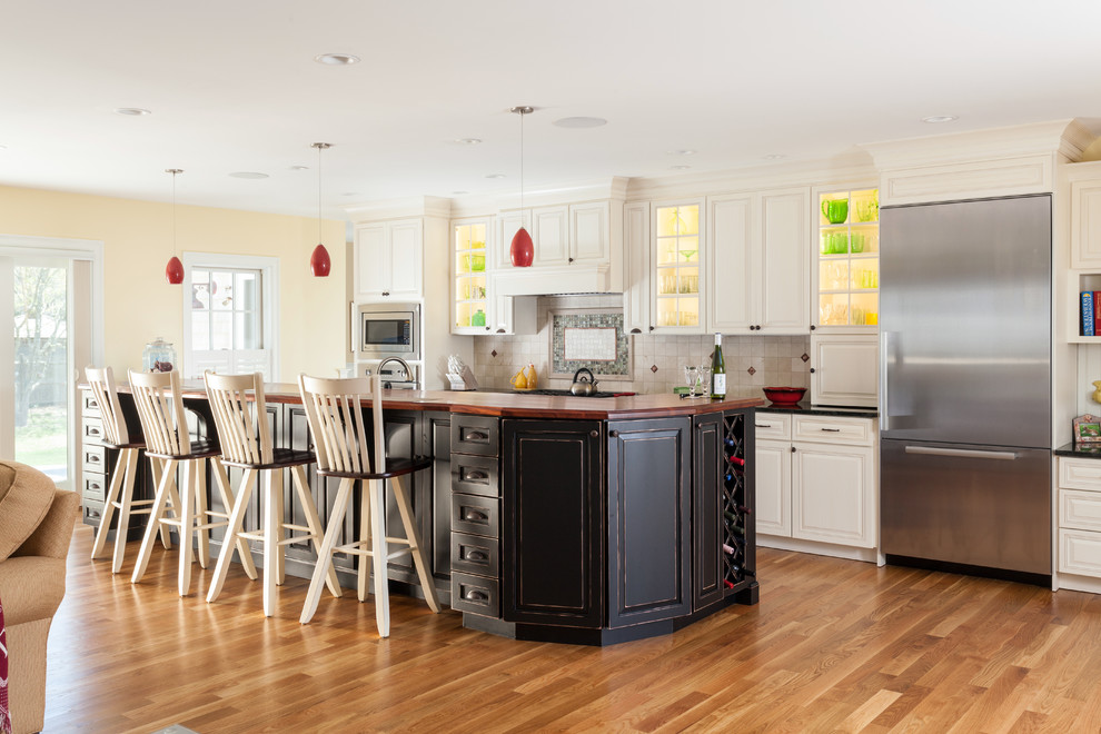 Offene Klassische Küche mit profilierten Schrankfronten, weißen Schränken, Küchenrückwand in Beige, Küchengeräten aus Edelstahl, braunem Holzboden und Kücheninsel in Boston