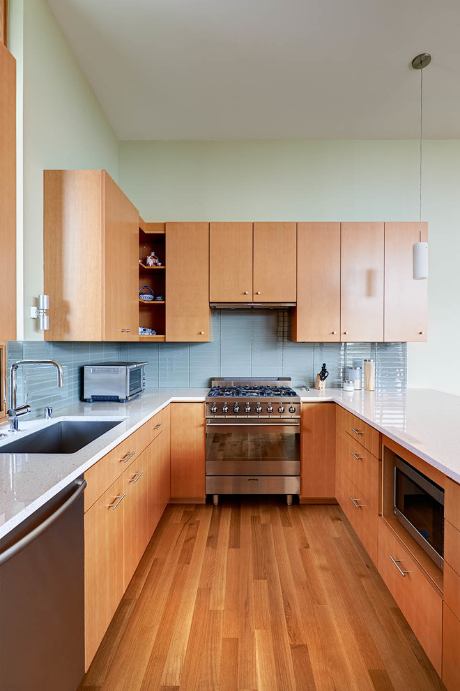 Moderne Küche mit Unterbauwaschbecken, Küchengeräten aus Edelstahl, flächenbündigen Schrankfronten, hellbraunen Holzschränken, Rückwand aus Glasfliesen und Küchenrückwand in Blau in Seattle