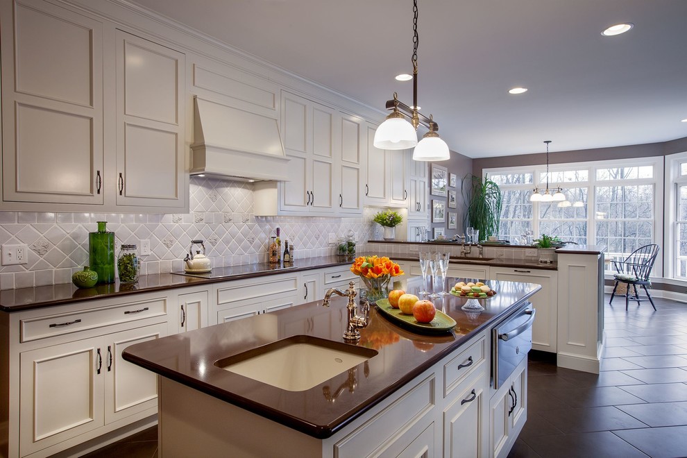 Photo of a large traditional l-shaped kitchen/diner in Philadelphia with a submerged sink, recessed-panel cabinets, white cabinets, grey splashback, ceramic splashback, an island, engineered stone countertops, stainless steel appliances and slate flooring.