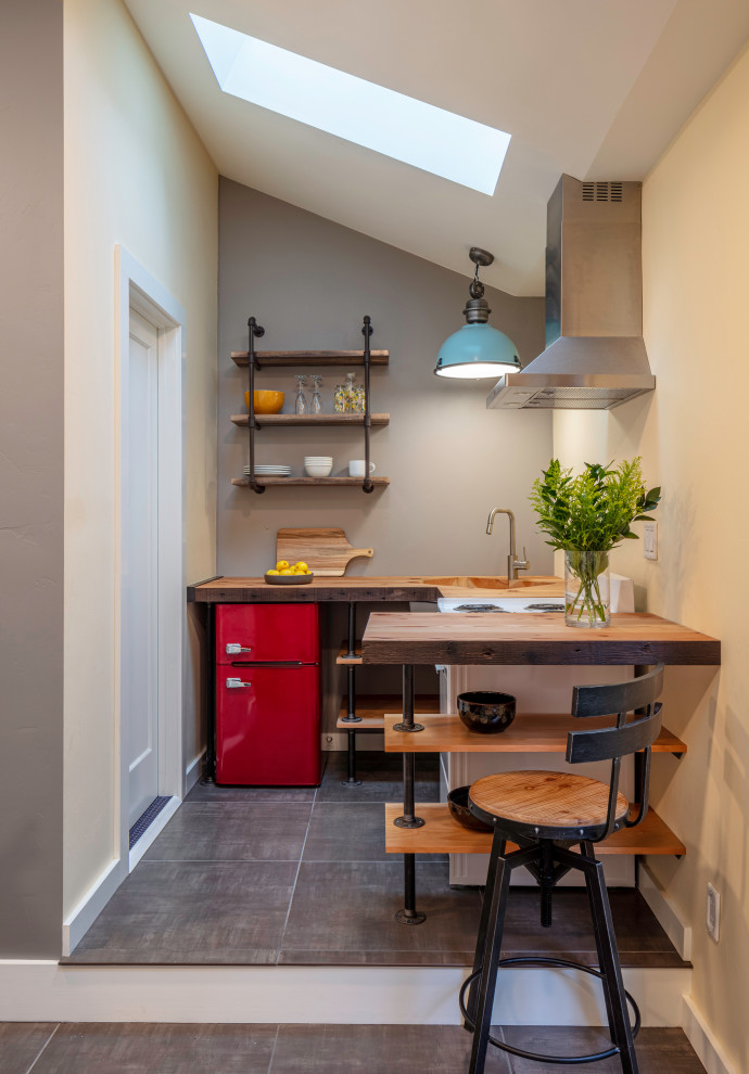 Photo of a small industrial u-shaped open plan kitchen in San Francisco with open cabinets, wood worktops, brown worktops, a submerged sink, coloured appliances, grey floors, a vaulted ceiling and a breakfast bar.