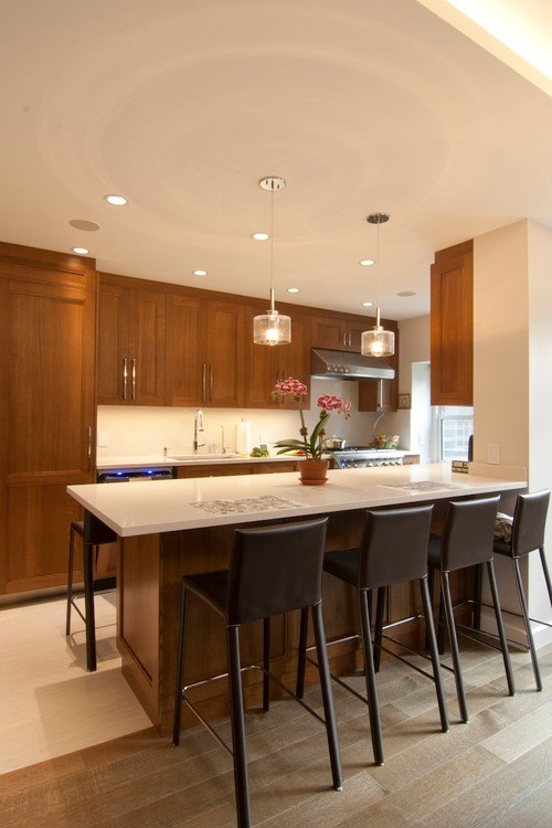 Example of a mid-sized minimalist galley light wood floor and beige floor eat-in kitchen design in New York with medium tone wood cabinets, white backsplash, a peninsula, an undermount sink, recessed-panel cabinets, quartz countertops, stone slab backsplash and paneled appliances