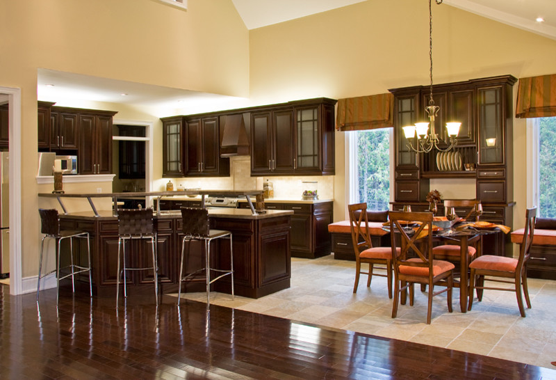 Example of a large classic l-shaped dark wood floor eat-in kitchen design in Toronto with an undermount sink, raised-panel cabinets, dark wood cabinets, granite countertops, beige backsplash, stainless steel appliances, a peninsula and multicolored countertops