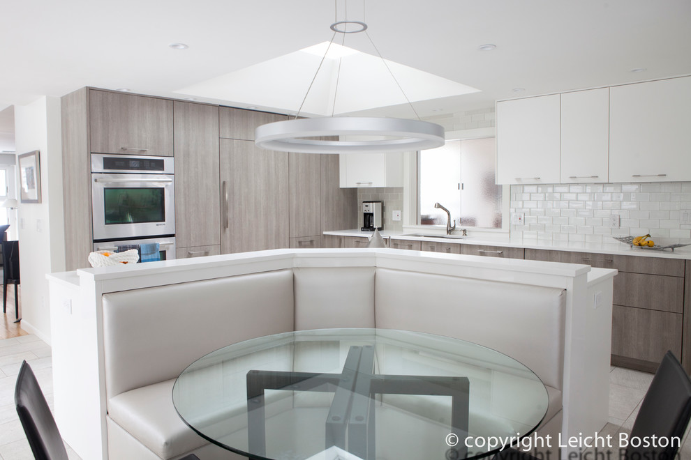 This is an example of a contemporary l-shaped kitchen/diner in Boston with an integrated sink, flat-panel cabinets, grey cabinets, grey splashback, metro tiled splashback, stainless steel appliances, porcelain flooring and an island.