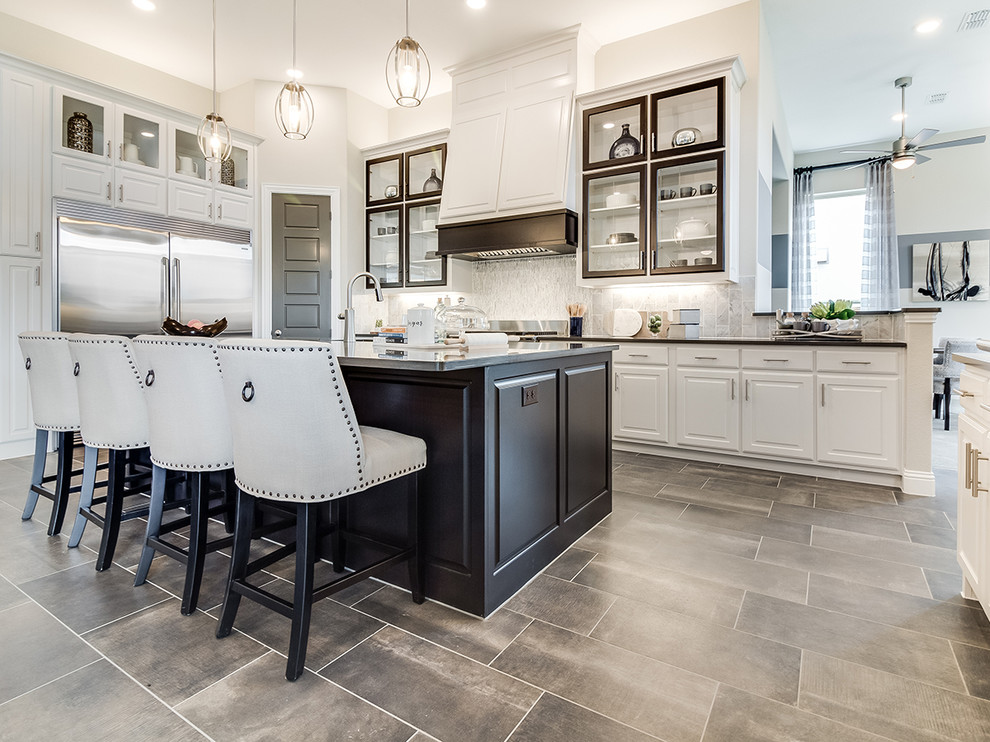 Open concept kitchen - large modern galley ceramic tile and gray floor open concept kitchen idea in Dallas with raised-panel cabinets, white cabinets, beige backsplash, stainless steel appliances and an island