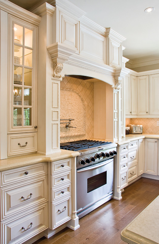 Example of a large classic u-shaped medium tone wood floor eat-in kitchen design in Toronto with an undermount sink, raised-panel cabinets, white cabinets, granite countertops, beige backsplash, limestone backsplash, stainless steel appliances, an island and beige countertops
