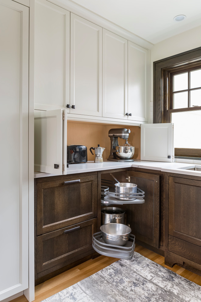 Design ideas for a small classic u-shaped kitchen/diner in Minneapolis with a double-bowl sink, dark wood cabinets, engineered stone countertops, white splashback, ceramic splashback, stainless steel appliances, light hardwood flooring, no island, brown floors and white worktops.