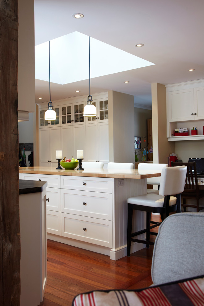 Elegant u-shaped eat-in kitchen photo in Toronto with a drop-in sink, recessed-panel cabinets, white cabinets, wood countertops, white backsplash and stainless steel appliances