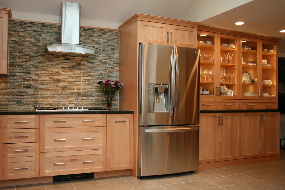 Bild på ett stort amerikanskt kök, med en undermonterad diskho, luckor med infälld panel, skåp i mellenmörkt trä, granitbänkskiva, flerfärgad stänkskydd, stänkskydd i stenkakel, rostfria vitvaror, klinkergolv i porslin och en köksö