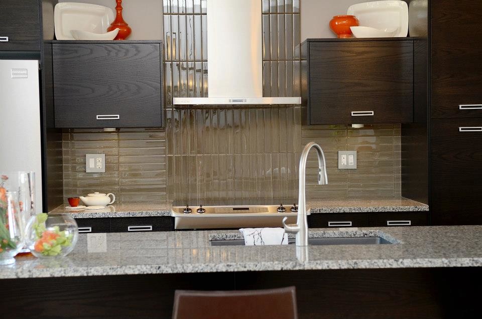 Esempio di una cucina minimal di medie dimensioni con lavello sottopiano, ante lisce, ante in legno bruno, top in granito, paraspruzzi grigio, paraspruzzi con lastra di vetro, elettrodomestici in acciaio inossidabile e parquet chiaro