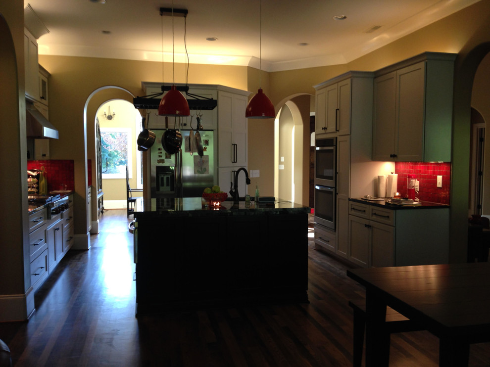 Exempel på ett stort modernt kök, med rött stänkskydd, stänkskydd i glaskakel, rostfria vitvaror, mörkt trägolv och en köksö
