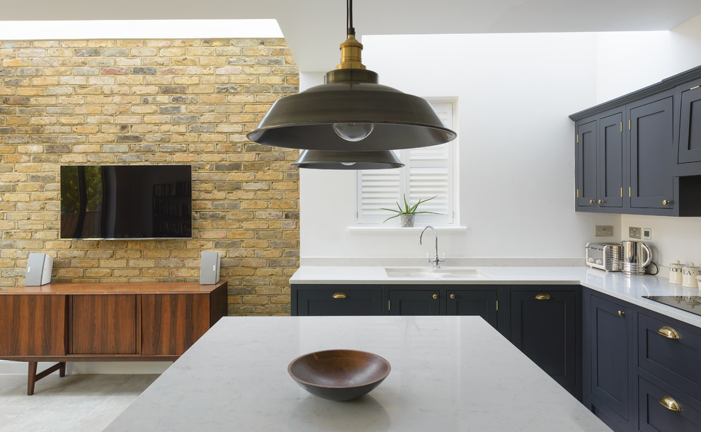 Classic kitchen/diner in London with shaker cabinets, dark wood cabinets, quartz worktops and an island.