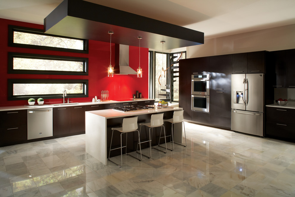 Immagine di un'ampia cucina design con lavello sottopiano, ante lisce, ante in legno bruno, top in superficie solida, paraspruzzi rosso, elettrodomestici in acciaio inossidabile e pavimento in marmo