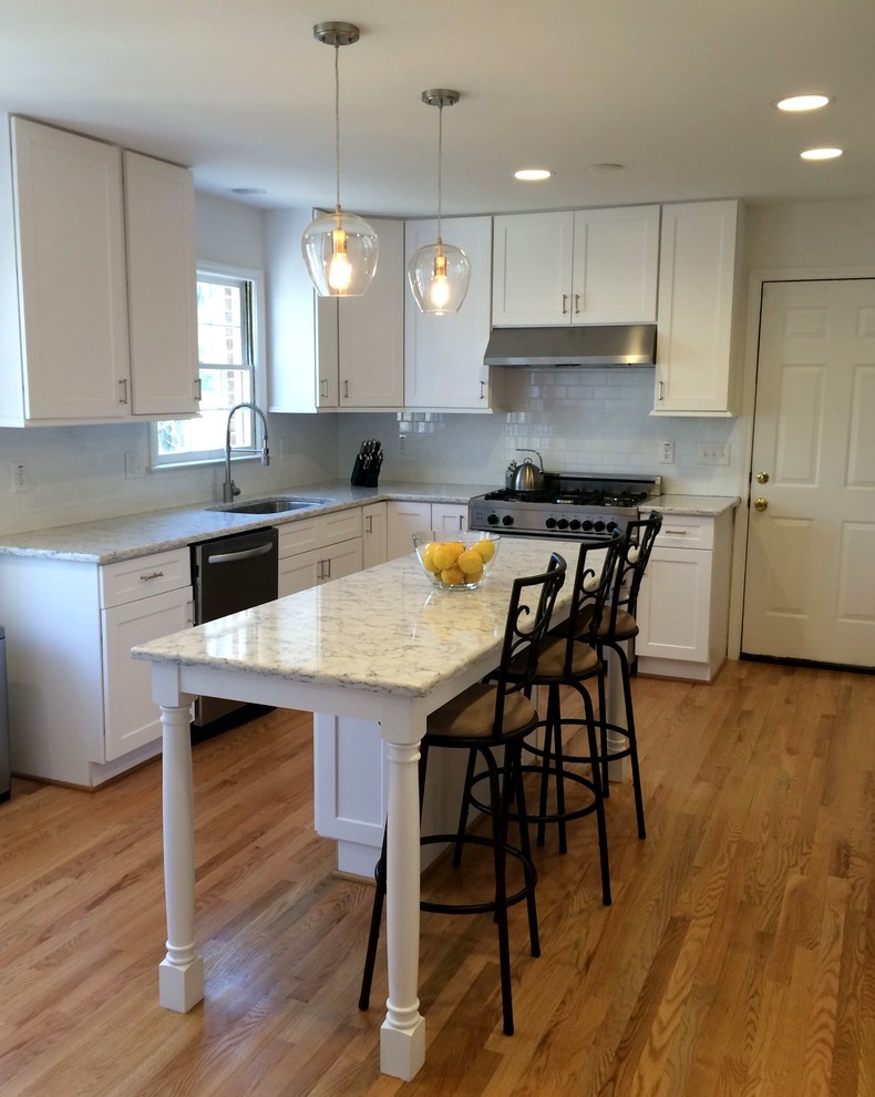 Inspiration for a small transitional l-shaped light wood floor eat-in kitchen remodel in Charleston with an undermount sink, white cabinets, quartz countertops, stainless steel appliances, shaker cabinets, white backsplash, subway tile backsplash and an island