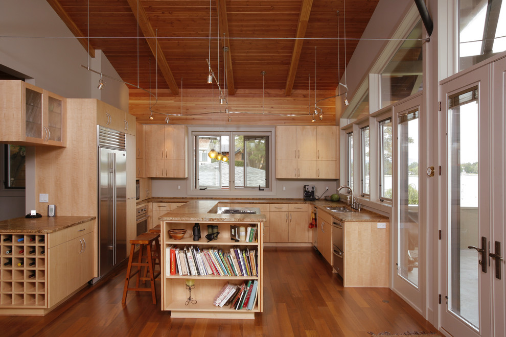 Aménagement d'une cuisine moderne en U et bois clair avec un plan de travail en granite, un électroménager en acier inoxydable et un placard à porte plane.