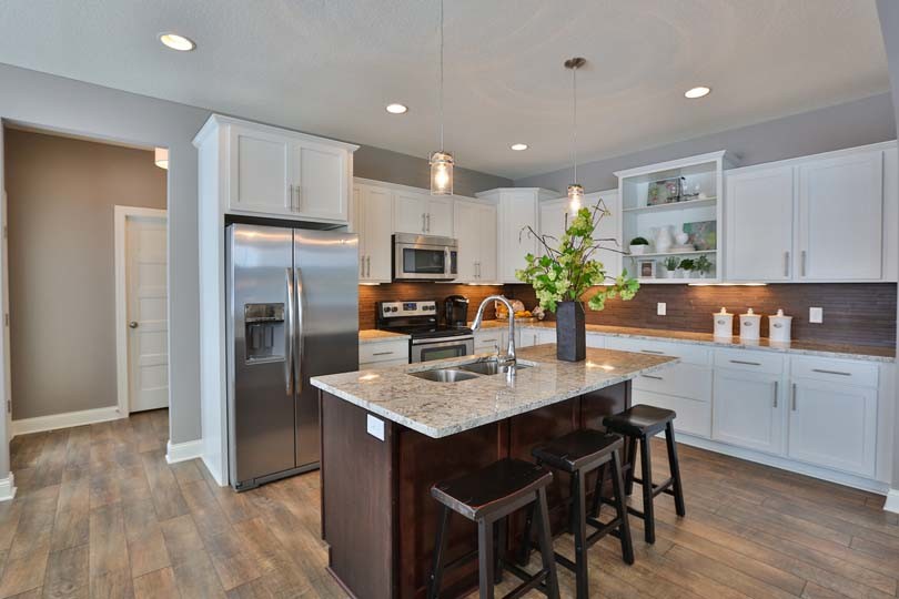 Example of a mid-sized classic l-shaped light wood floor eat-in kitchen design in Minneapolis with a double-bowl sink, recessed-panel cabinets, white cabinets, granite countertops, beige backsplash, ceramic backsplash, stainless steel appliances and an island