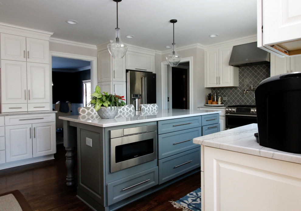 Example of a large transitional u-shaped dark wood floor and brown floor kitchen design in Chicago with a farmhouse sink, raised-panel cabinets, white cabinets, quartzite countertops, gray backsplash, glass tile backsplash, stainless steel appliances, an island and multicolored countertops