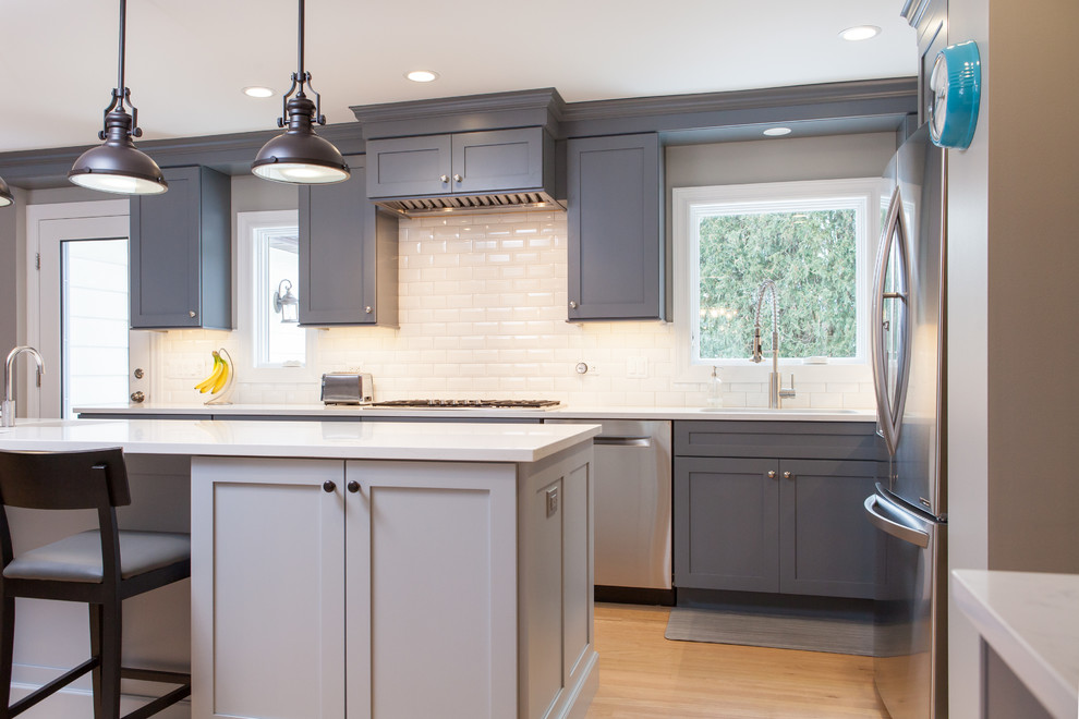 Eat-in kitchen - large transitional galley light wood floor eat-in kitchen idea in Chicago with a drop-in sink, beaded inset cabinets, gray cabinets, quartz countertops, white backsplash, subway tile backsplash, stainless steel appliances and an island
