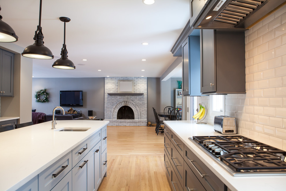Example of a large transitional galley light wood floor eat-in kitchen design in Chicago with a drop-in sink, beaded inset cabinets, gray cabinets, quartz countertops, white backsplash, subway tile backsplash, stainless steel appliances and an island