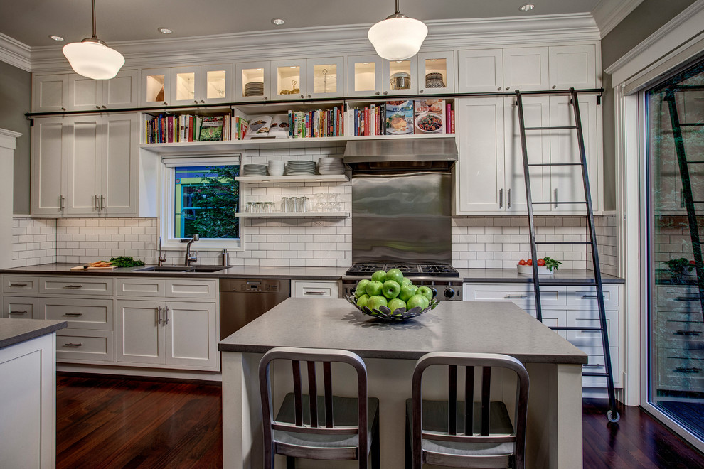 Foto på ett amerikanskt linjärt kök, med en dubbel diskho, skåp i shakerstil, vita skåp, vitt stänkskydd, stänkskydd i tunnelbanekakel, rostfria vitvaror och en köksö