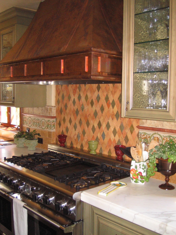 オレンジカウンティにある広い地中海スタイルのおしゃれなキッチン (ガラス扉のキャビネット、ベージュのキャビネット、クオーツストーンカウンター、マルチカラーのキッチンパネル、セラミックタイルのキッチンパネル、シルバーの調理設備) の写真
