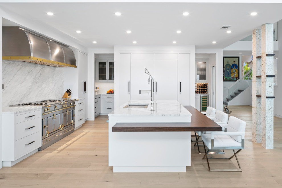 Idéer för mellanstora funkis vitt kök och matrum, med en undermonterad diskho, luckor med profilerade fronter, vita skåp, marmorbänkskiva, vitt stänkskydd, stänkskydd i marmor, rostfria vitvaror, ljust trägolv, en köksö och beiget golv