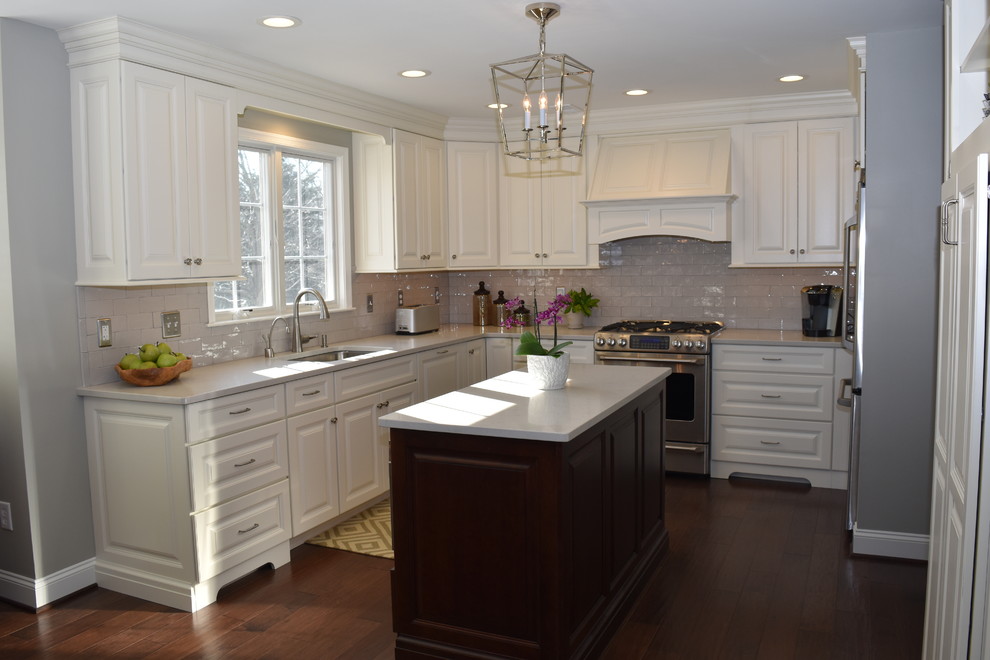 Exempel på ett mellanstort klassiskt kök, med en undermonterad diskho, luckor med upphöjd panel, vita skåp, bänkskiva i kvarts, grått stänkskydd, stänkskydd i keramik, rostfria vitvaror, mörkt trägolv och en köksö