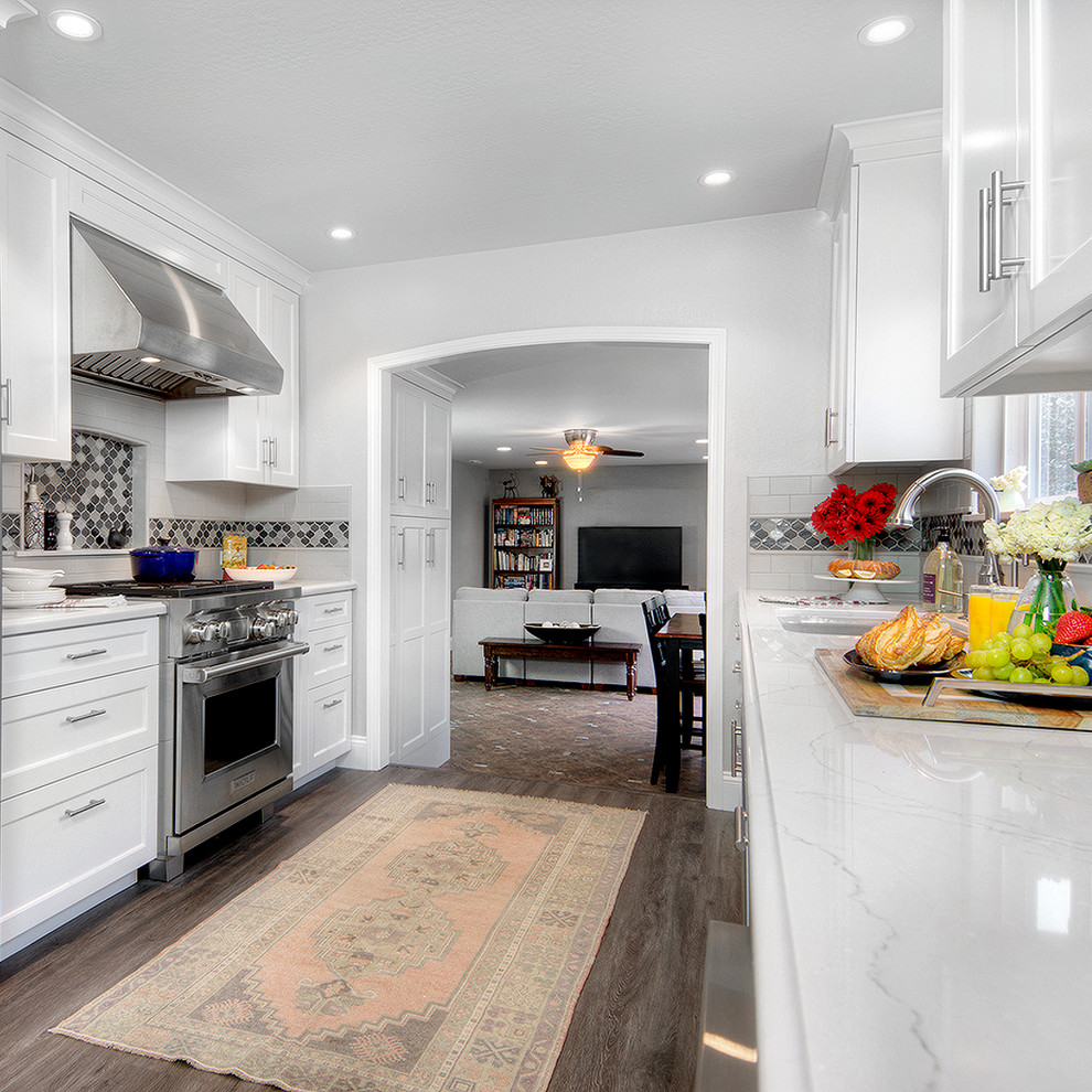 Exempel på ett mellanstort klassiskt vit vitt kök, med en undermonterad diskho, skåp i shakerstil, vita skåp, bänkskiva i kvarts, flerfärgad stänkskydd, stänkskydd i mosaik, rostfria vitvaror, vinylgolv och brunt golv