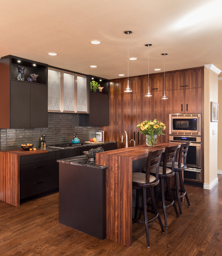Moderne Küche mit flächenbündigen Schrankfronten, braunen Schränken, Küchenrückwand in Metallic, Küchengeräten aus Edelstahl, dunklem Holzboden, Kücheninsel und braunem Boden in Denver