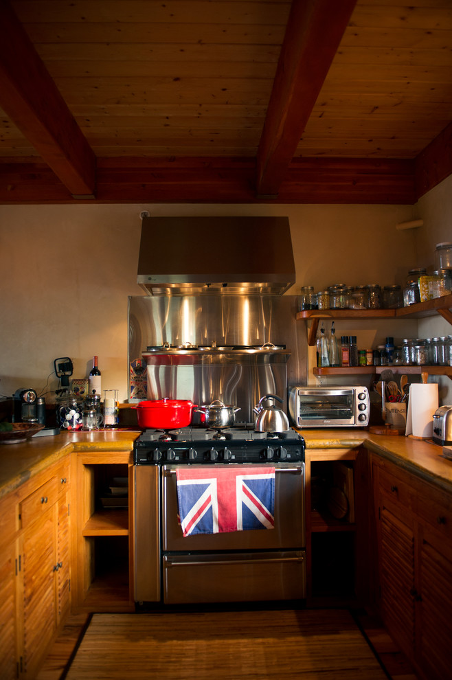 Imagen de cocina tropical con puertas de armario de madera oscura, encimera de madera y electrodomésticos de acero inoxidable