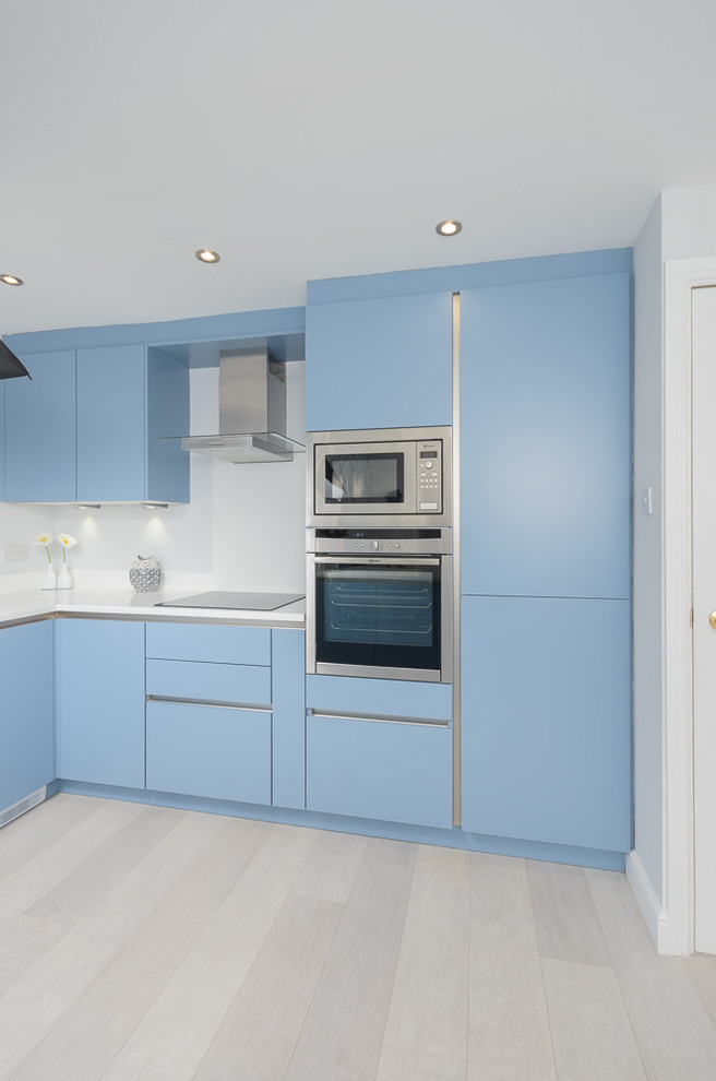 Modern inredning av ett mellanstort kök, med släta luckor, blå skåp, bänkskiva i koppar, vitt stänkskydd, integrerade vitvaror och linoleumgolv