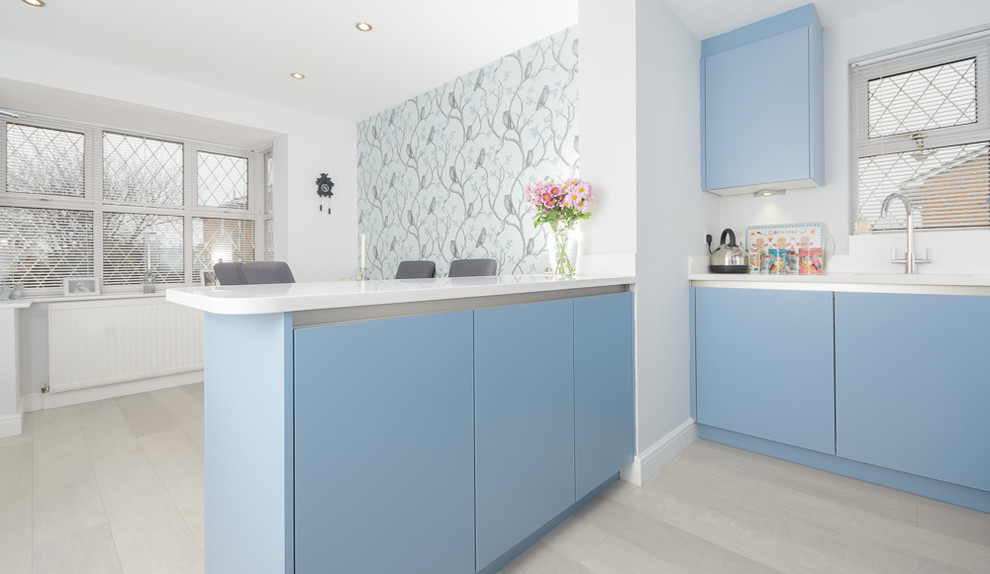 Esempio di una cucina moderna di medie dimensioni con lavello integrato, ante lisce, ante blu, top in superficie solida, paraspruzzi bianco, elettrodomestici da incasso, pavimento in linoleum e penisola