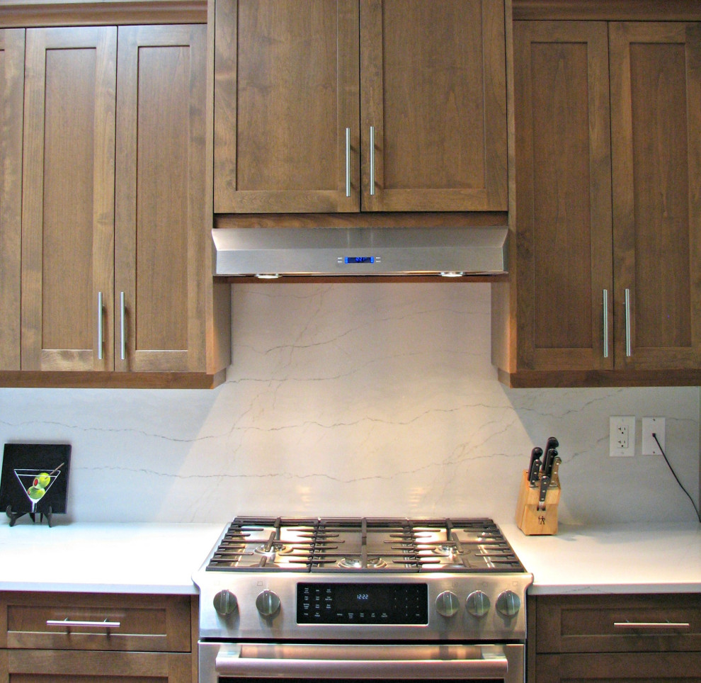 Inredning av ett lantligt mellanstort vit vitt kök, med en dubbel diskho, skåp i shakerstil, skåp i mellenmörkt trä, bänkskiva i kvarts, vitt stänkskydd, stänkskydd i sten, rostfria vitvaror, mellanmörkt trägolv och en köksö