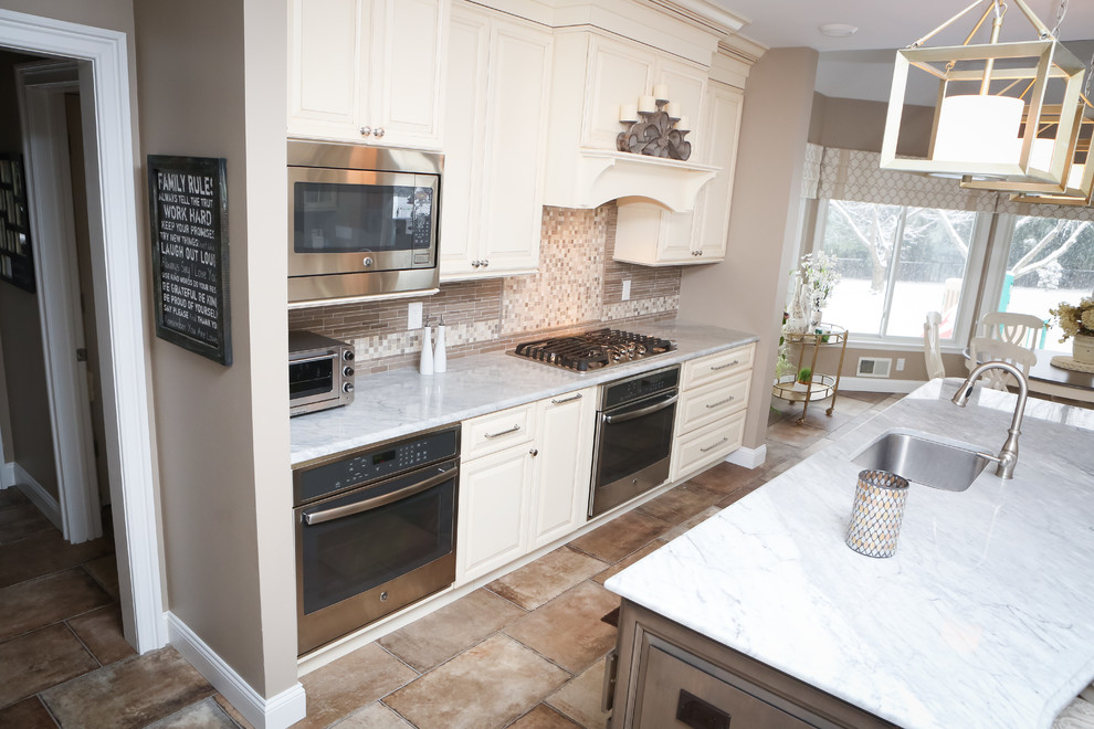 Example of a large classic u-shaped ceramic tile eat-in kitchen design in Newark with an undermount sink, raised-panel cabinets, white cabinets, quartz countertops, multicolored backsplash, ceramic backsplash, stainless steel appliances and an island